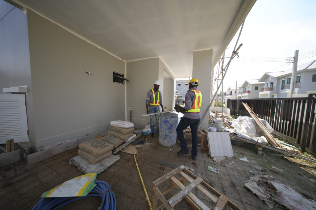 Construction workers prepare materials at a residential site in the afternoon sun